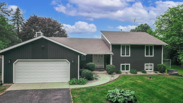 7640 W H Ave, Kalamazoo, MI 49009 - split level home featuring a front yard, asphalt driveway, a chimney, a garage, and roof with shingles