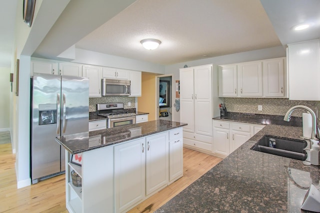 7640 W H Ave, Kalamazoo, MI 49009 - kitchen with appliances with stainless steel finishes, light wood-type flooring, a kitchen island, and white cabinets