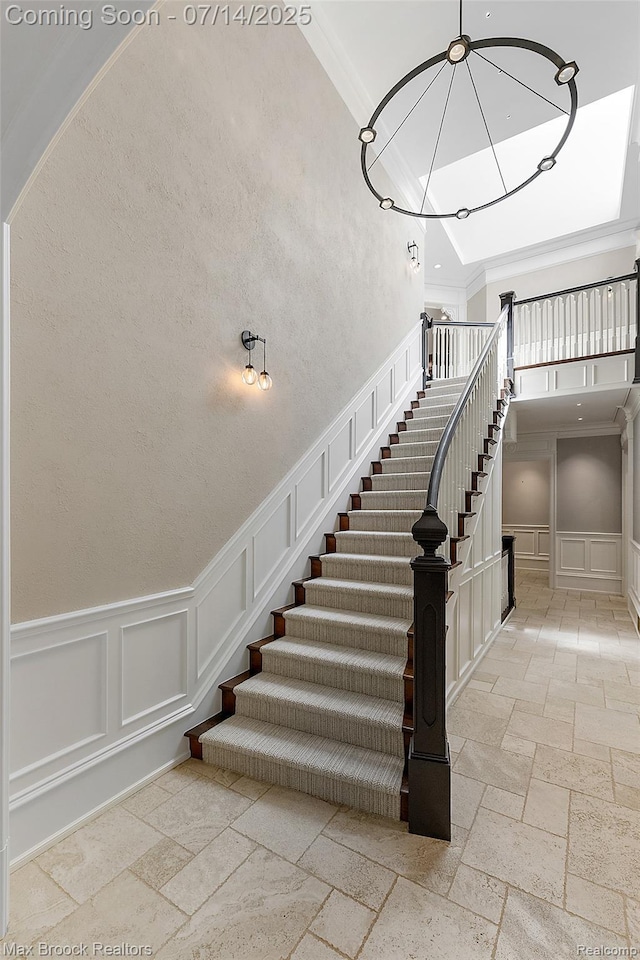 7420 Inner Circle Dr, Bloomfield Hills, MI 48301 - stairway featuring a decorative wall, stone tile floors, crown molding, a towering ceiling, and a wainscoted wall