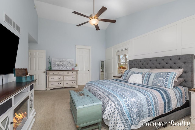 8790 Laurel Ridge Dr SE, Alto, MI 49302 - bedroom with high vaulted ceiling, light carpet, a decorative wall, and ceiling fan