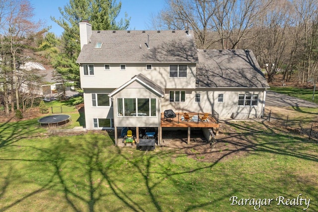 8790 Laurel Ridge Dr SE, Alto, MI 49302 - rear view of house with a trampoline, a wooden deck, and a chimney