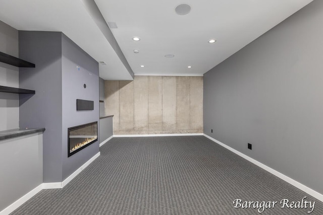 8790 Laurel Ridge Dr SE, Alto, MI 49302 - unfurnished living room with dark carpet, recessed lighting, and a glass covered fireplace