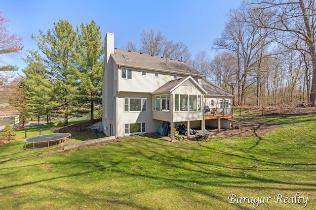 8790 Laurel Ridge Dr SE, Alto, MI 49302 - back of house with a trampoline, a sunroom, a chimney, and a yard