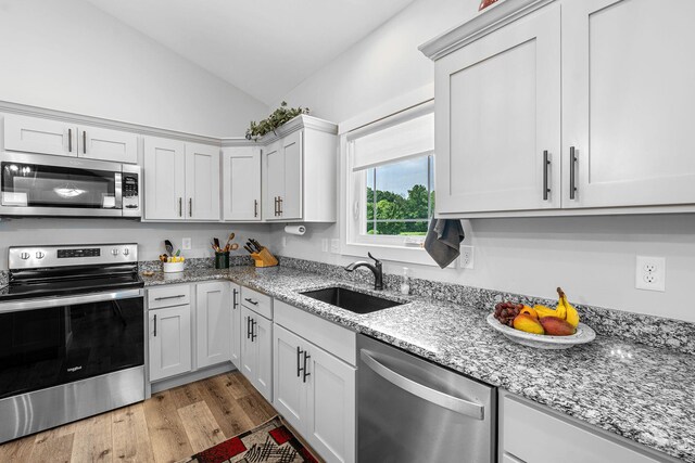 14170 Spring Valley Ct, Niles, MI 49120 - kitchen with stainless steel appliances, vaulted ceiling, light wood finished floors, light stone counters, and white cabinets