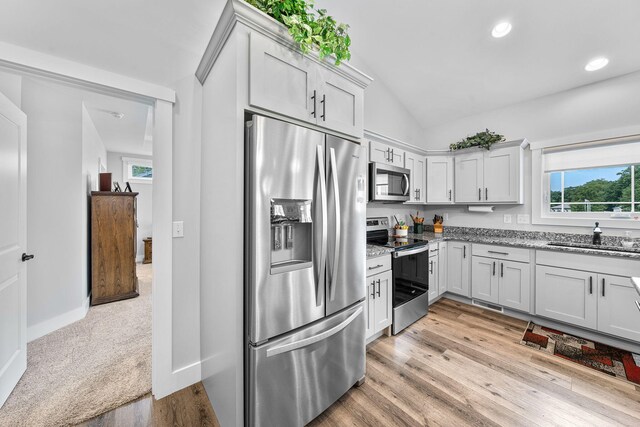 14170 Spring Valley Ct, Niles, MI 49120 - kitchen featuring appliances with stainless steel finishes, vaulted ceiling, light stone countertops, light wood-type flooring, and recessed lighting