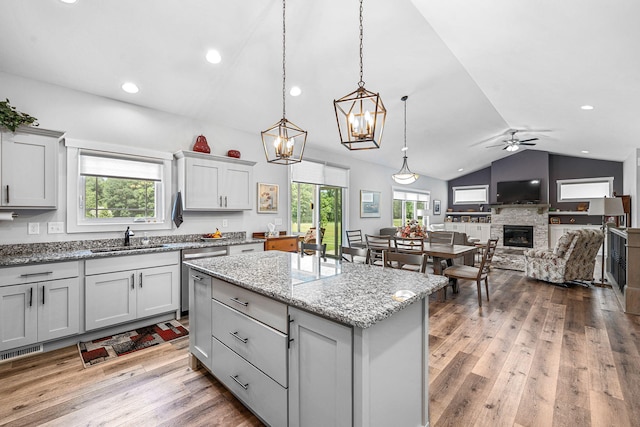14170 Spring Valley Ct, Niles, MI 49120 - kitchen with vaulted ceiling, a fireplace, a kitchen island, a ceiling fan, and light wood-style floors