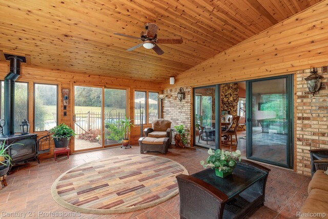 9601 Kier Rd, Holly, MI 48442 - living area with a wood stove, vaulted ceiling, a ceiling fan, and wooden walls