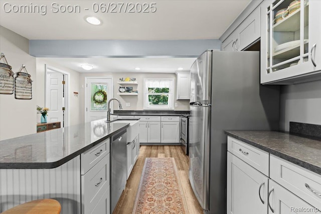 1500 Clark Lake Rd, Brighton, MI 48114 - kitchen featuring light wood-type flooring, appliances with stainless steel finishes, dark stone countertops, a center island with sink, and glass insert cabinets