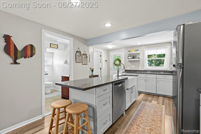 1500 Clark Lake Rd, Brighton, MI 48114 - kitchen with appliances with stainless steel finishes, a kitchen breakfast bar, dark countertops, a center island with sink, and wood finished floors