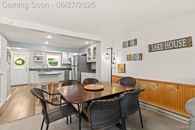 1500 Clark Lake Rd, Brighton, MI 48114 - dining space with baseboard heating, wainscoting, light wood finished floors, wooden walls, and recessed lighting