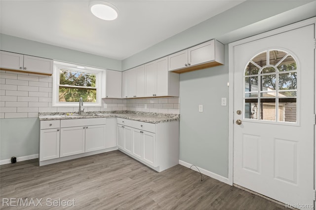 1413 Martha Ave, Burton, MI 48509 - kitchen with tasteful backsplash, white cabinetry, light stone counters, and light wood finished floors