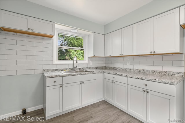 1413 Martha Ave, Burton, MI 48509 - kitchen featuring decorative backsplash, white cabinetry, light wood finished floors, and light stone counters