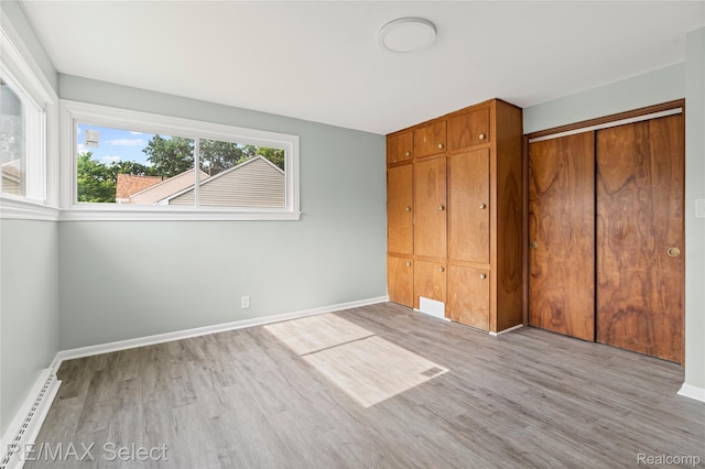 1413 Martha Ave, Burton, MI 48509 - unfurnished bedroom with a baseboard heating unit, wood finished floors, and a closet