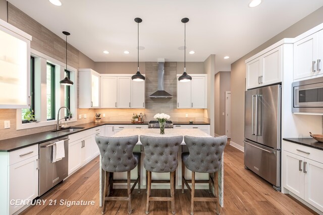 2985 E Iron Woods Pass, Midland, MI 48642 - kitchen with premium appliances, wall chimney range hood, a kitchen island, tasteful backsplash, and a kitchen breakfast bar