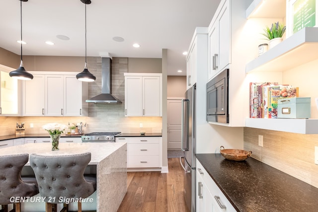 2985 E Iron Woods Pass, Midland, MI 48642 - kitchen with wall chimney range hood, stainless steel appliances, tasteful backsplash, light wood-style flooring, and white cabinetry