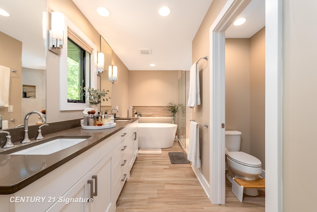 2985 E Iron Woods Pass, Midland, MI 48642 - bathroom with double vanity, a freestanding bath, wood finished floors, and recessed lighting