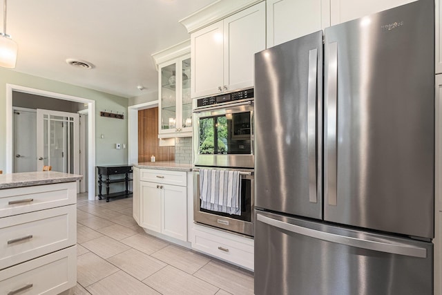 2507 Riverwood Ter, Saint Joseph, MI 49085 - kitchen featuring appliances with stainless steel finishes, glass insert cabinets, light stone counters, decorative backsplash, and white cabinetry