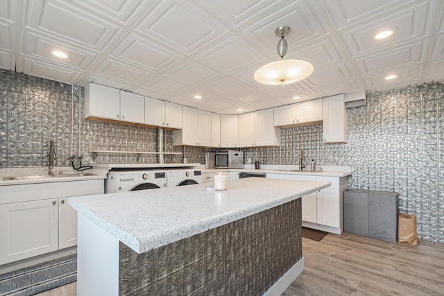 2507 Riverwood Ter, Saint Joseph, MI 49085 - kitchen featuring appliances with stainless steel finishes, white cabinets, an ornate ceiling, independent washer and dryer, and light wood-type flooring