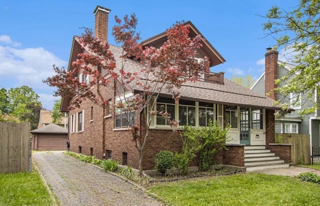 2313 S Westnedge Ave, Kalamazoo, MI 49008 - view of front of house featuring a chimney, brick siding, a detached garage, roof with shingles, and a sunroom