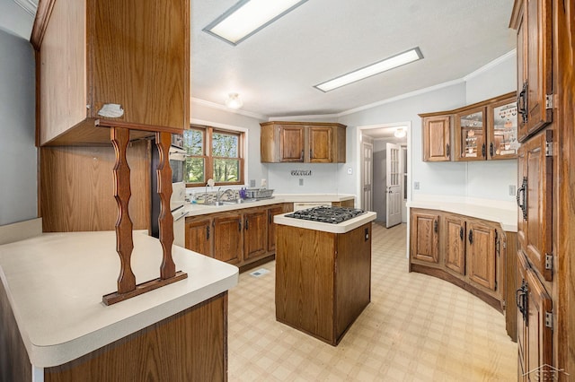11816 Morton Rd, Manistee, MI 49660 - kitchen featuring ornamental molding, brown cabinetry, vaulted ceiling, light countertops, and gas stovetop