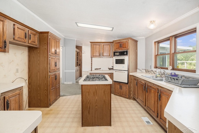 11816 Morton Rd, Manistee, MI 49660 - kitchen featuring double oven, a kitchen island, brown cabinets, stainless steel gas cooktop, and light countertops