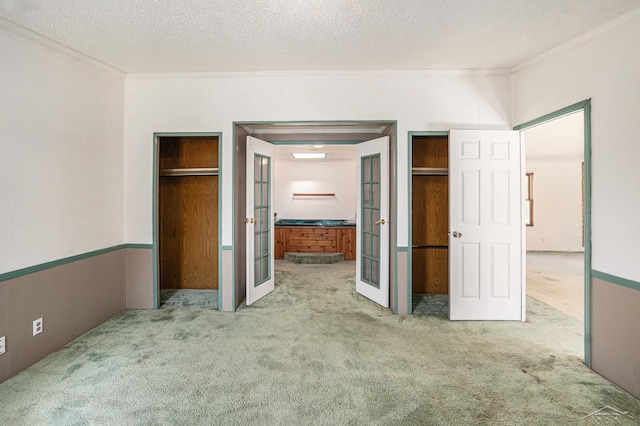 11816 Morton Rd, Manistee, MI 49660 - unfurnished bedroom featuring french doors, ornamental molding, carpet flooring, a textured ceiling, and connected bathroom