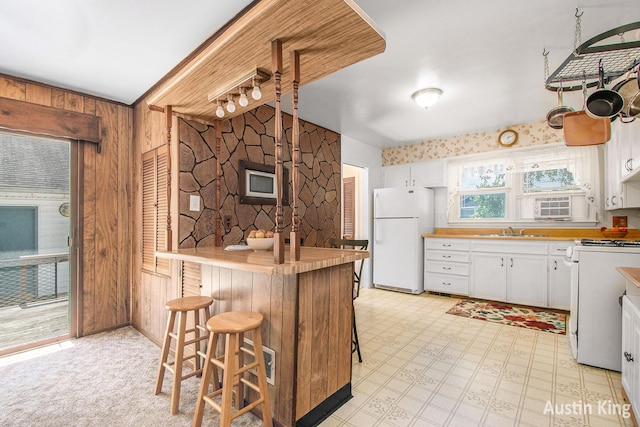 3156 Tuell St NW, Grand Rapids, MI 49504 - kitchen featuring white appliances, wood walls, white cabinetry, light countertops, and light floors