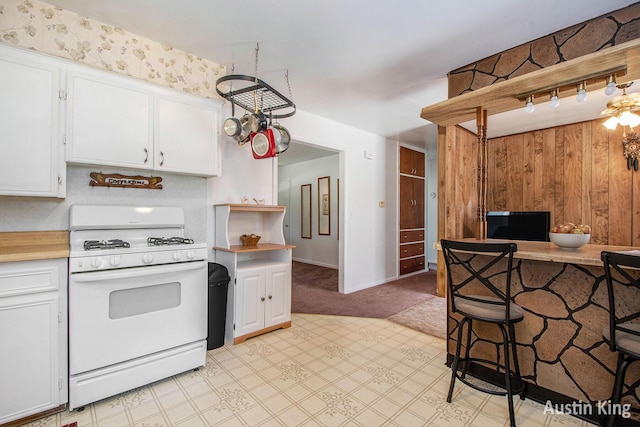 3156 Tuell St NW, Grand Rapids, MI 49504 - kitchen featuring white gas range oven, light countertops, white cabinetry, light floors, and wood walls