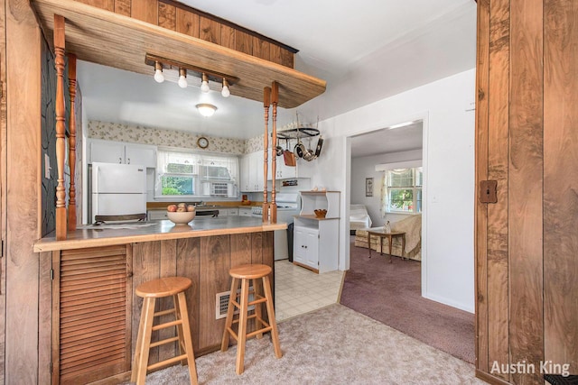 3156 Tuell St NW, Grand Rapids, MI 49504 - kitchen with freestanding refrigerator, light colored carpet, white cabinets, a breakfast bar, and open shelves