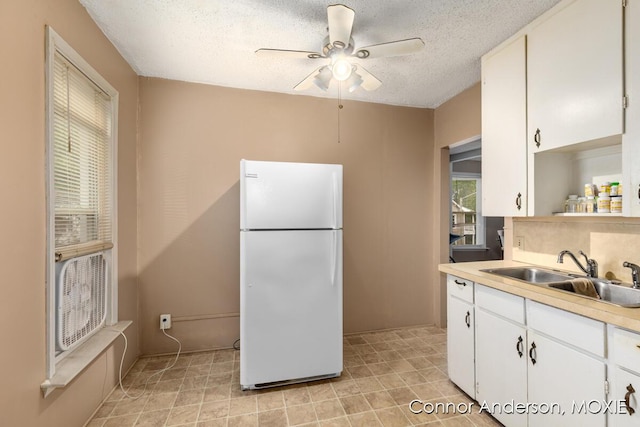 1523 Broadway Ave NW, Grand Rapids, MI 49504 - kitchen featuring freestanding refrigerator, white cabinetry, ceiling fan, light countertops, and a textured ceiling
