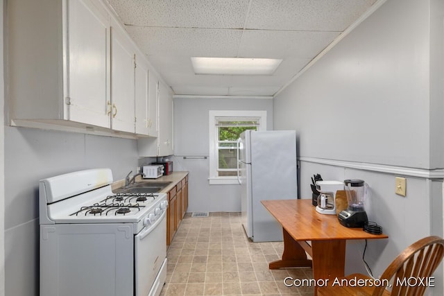 1523 Broadway Ave NW, Grand Rapids, MI 49504 - kitchen featuring white appliances, a paneled ceiling, white cabinets, and light countertops