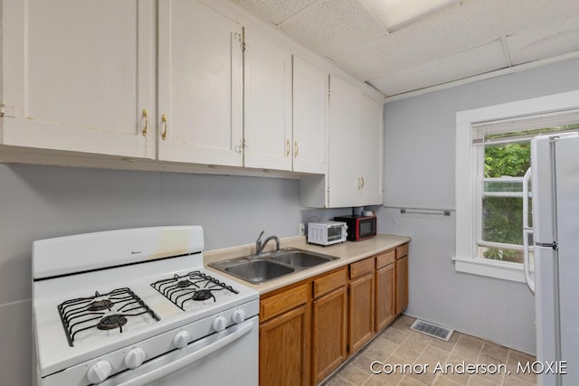 1523 Broadway Ave NW, Grand Rapids, MI 49504 - kitchen with white appliances, a paneled ceiling, light countertops, and brown cabinets