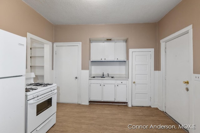 1523 Broadway Ave NW, Grand Rapids, MI 49504 - kitchen featuring white appliances, white cabinetry, light countertops, light wood-style flooring, and a textured ceiling