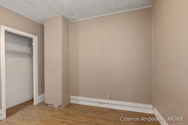 1523 Broadway Ave NW, Grand Rapids, MI 49504 - unfurnished bedroom featuring wood finished floors, a textured ceiling, and wooden walls