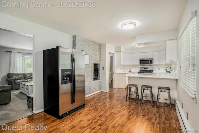 181 S Josephine Ave, Pontiac, MI 48341 - kitchen with stainless steel appliances, wood finished floors, white cabinets, a peninsula, and a kitchen breakfast bar