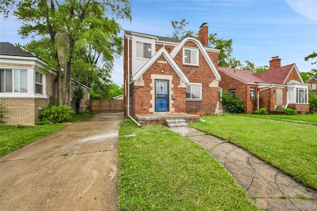 10825 E Outer Dr, Detroit, MI 48224 - tudor house with brick siding, concrete driveway, and a chimney