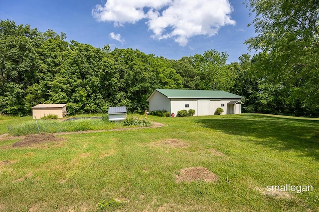 3192 W Sisson Rd, Freeport, MI 49325 - view of green lawn featuring an outbuilding, a wooded view, and a garage