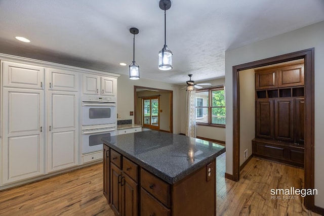 3192 W Sisson Rd, Freeport, MI 49325 - kitchen with double oven, light wood-style floors, white cabinetry, a kitchen island, and pendant lighting