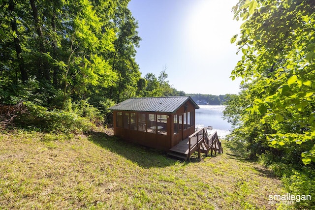 3192 W Sisson Rd, Freeport, MI 49325 - back of house featuring a water view, a sunroom, a metal roof, and a lawn