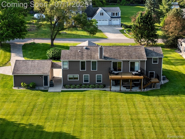 5131 Navajo Trl, Pinckney, MI 48169 - rear view of house with a wooden deck, a lawn, a chimney, a garage, and concrete driveway