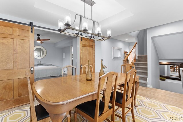 680 Breyman Hwy, Tipton, MI 49287 - dining room with a barn door, a chandelier, ceiling fan, wood finished floors, and stairway