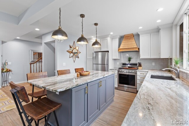 680 Breyman Hwy, Tipton, MI 49287 - kitchen with appliances with stainless steel finishes, custom range hood, white cabinets, a kitchen bar, and light wood-style flooring
