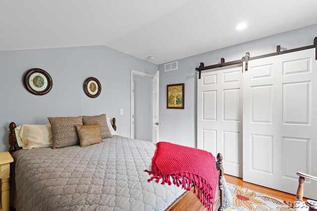 680 Breyman Hwy, Tipton, MI 49287 - bedroom with light wood-type flooring, vaulted ceiling, a closet, and a barn door