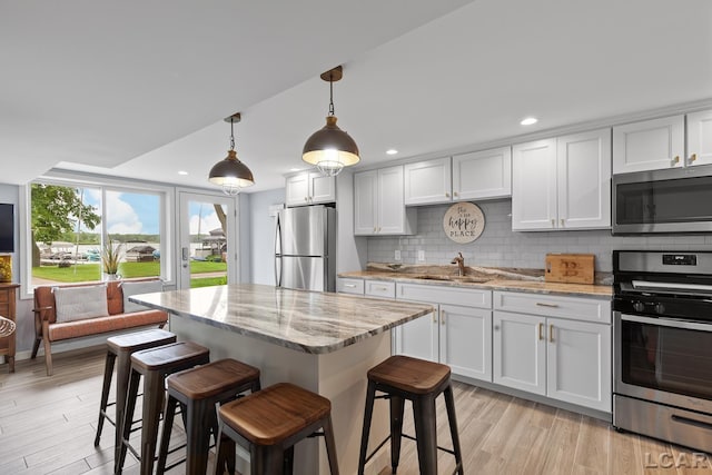 680 Breyman Hwy, Tipton, MI 49287 - kitchen with stainless steel appliances, light stone countertops, light wood-type flooring, decorative backsplash, and a kitchen bar