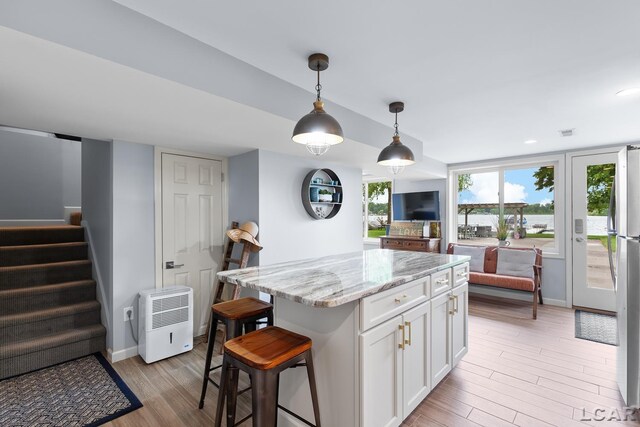 680 Breyman Hwy, Tipton, MI 49287 - kitchen with white cabinetry, light wood finished floors, open floor plan, light stone counters, and pendant lighting