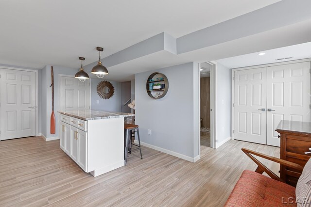 680 Breyman Hwy, Tipton, MI 49287 - kitchen with white cabinets, a kitchen bar, light stone countertops, light wood-style floors, and recessed lighting