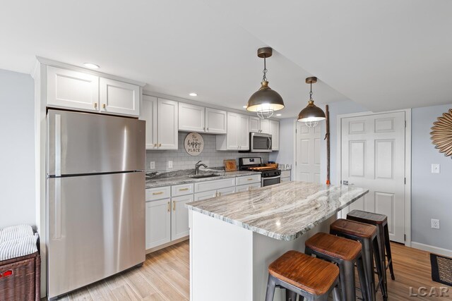680 Breyman Hwy, Tipton, MI 49287 - kitchen featuring stainless steel appliances, light wood-type flooring, white cabinetry, a kitchen island, and a kitchen bar