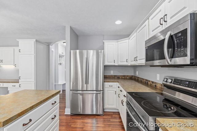 950 Whitetail Ct, Ionia, MI 48846 - kitchen featuring stainless steel appliances, dark wood-style floors, white cabinets, arched walkways, and recessed lighting