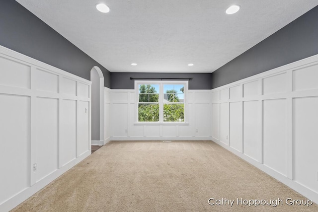 950 Whitetail Ct, Ionia, MI 48846 - unfurnished bedroom with a decorative wall, light carpet, arched walkways, recessed lighting, and a wainscoted wall