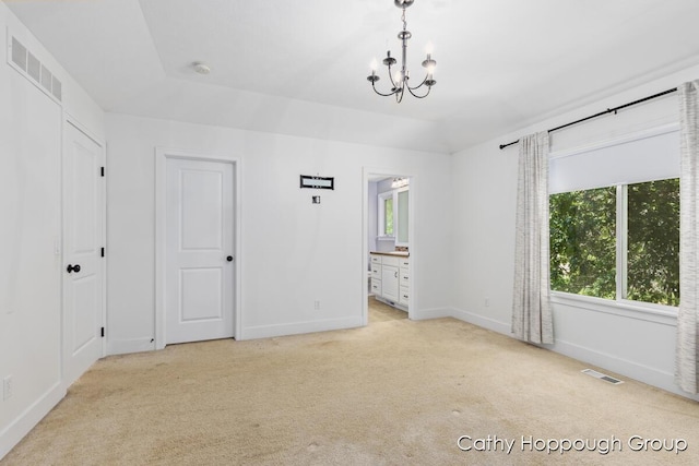 950 Whitetail Ct, Ionia, MI 48846 - unfurnished bedroom featuring light carpet, a chandelier, and ensuite bath